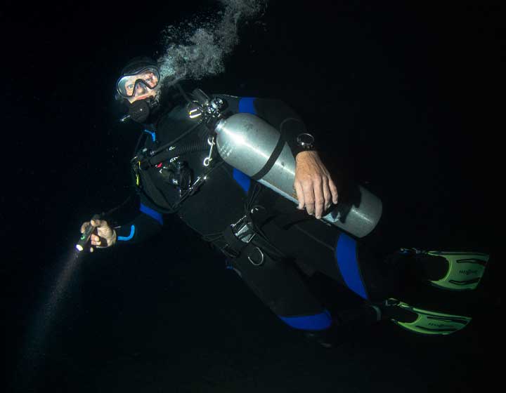 Image for the Night & Limited Visibility Specialty course, showcasing a diver with a flashlight exploring underwater in low visibility.