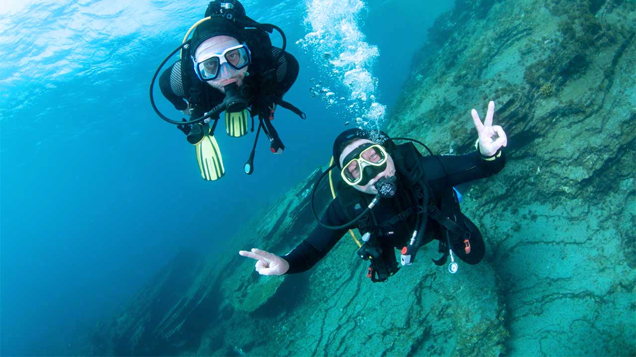 Two divers underwater during the Open Water Course in Tenerife with LoCura Diving, practicing skills near volcanic reefs and marine life.