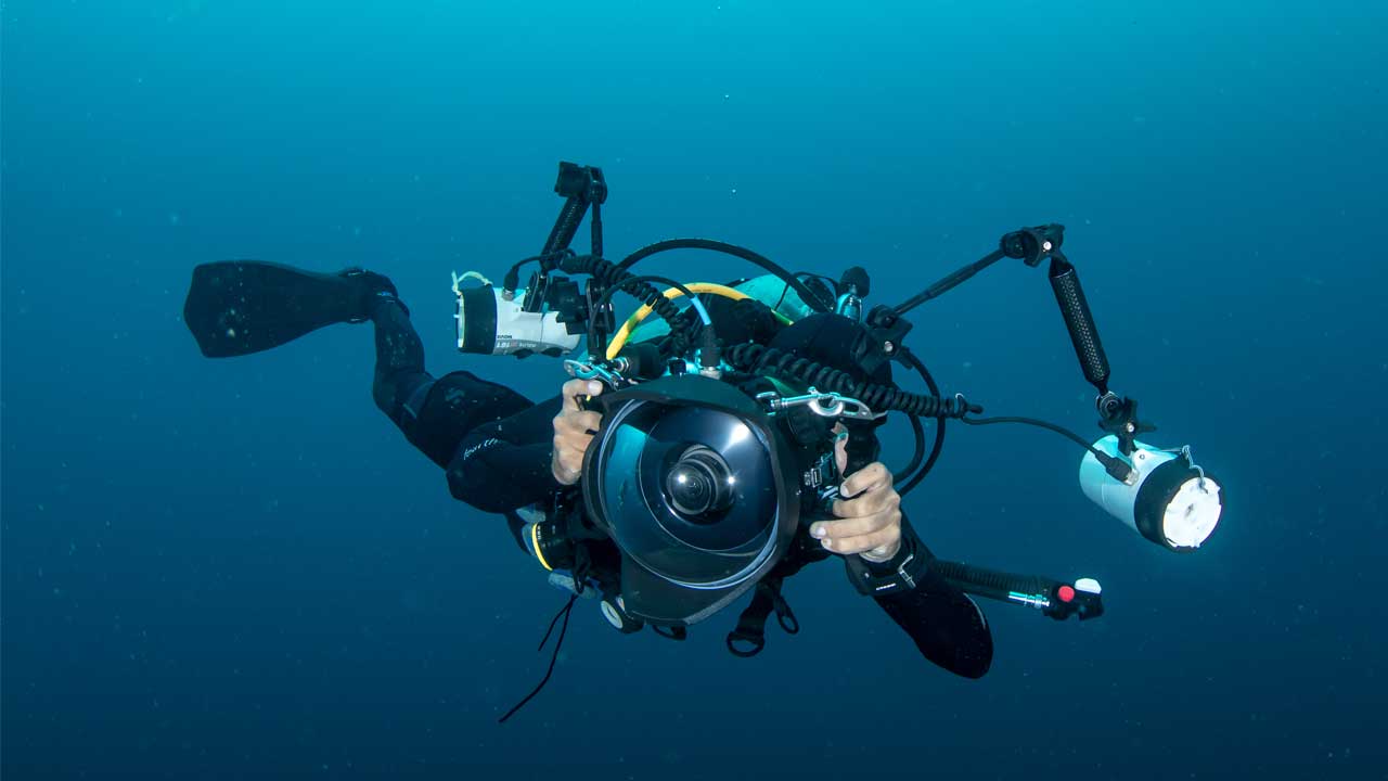 Underwater photographer with a professional camera capturing marine life in the clear blue waters of Tenerife during a dive with LoCura Diving.